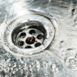 Stainless steel sink plug hole close up with water