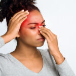 An African American Woman Holding Her Nose and Head That Are Highlighted in Red Can Chronic Sinusitis Affect Your Whole Body