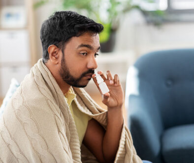 A Man Sitting on His Couch Wrapped in a Blanket Using Nasal Spray to Clear His Nose Can Nasal Spray Cause Loss of Smell