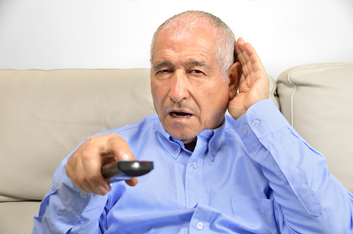Man with hearing loss turns the volume up on the television.