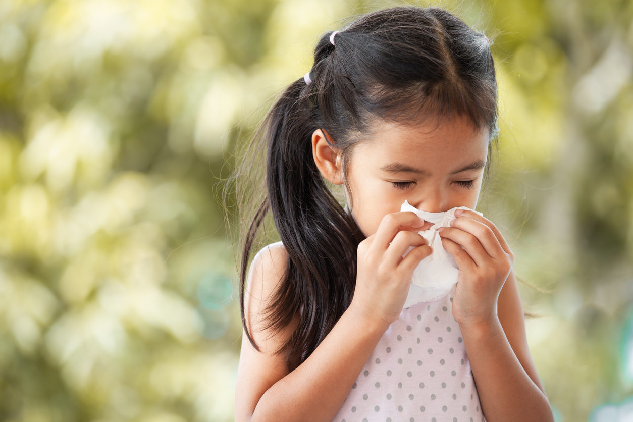 Child blows her nose, sick with the common cold.